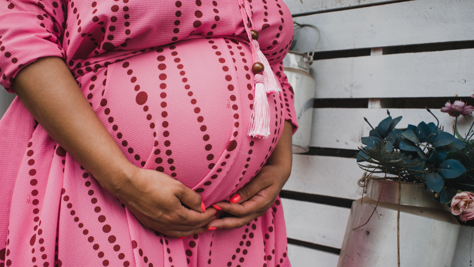 Pregnant woman holding her stomach wearing a pink dress