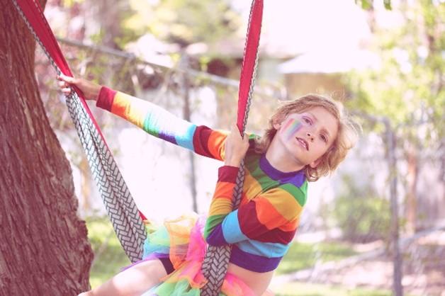 teen dressed in rainbow clothes on a swing