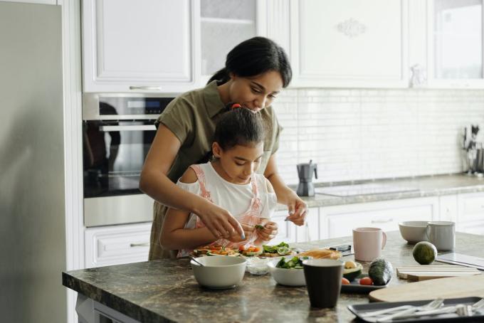young girl helping adult woman cook healthy food